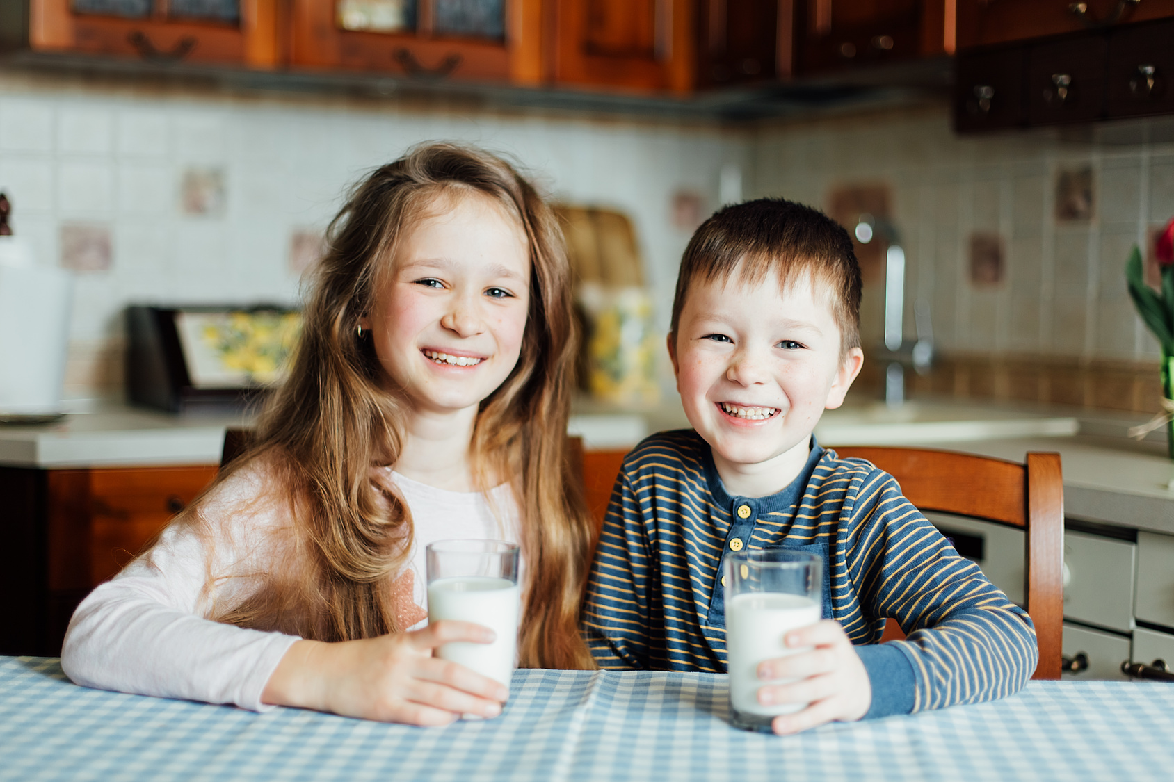 Children drink milk and have fun in the kitchen at the morning Children drink milk and have fun in the kitchen at the morning